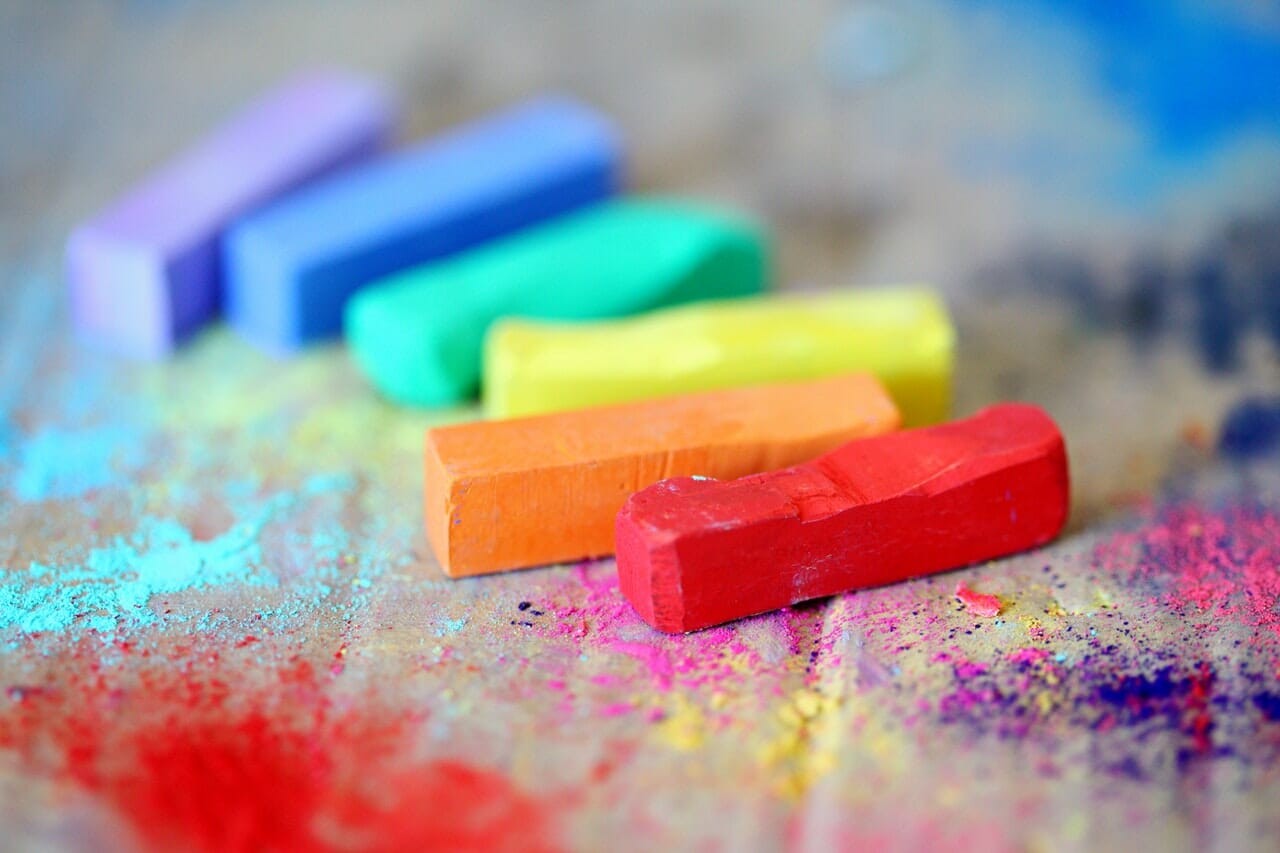 assorted colored chalks on wooden surface