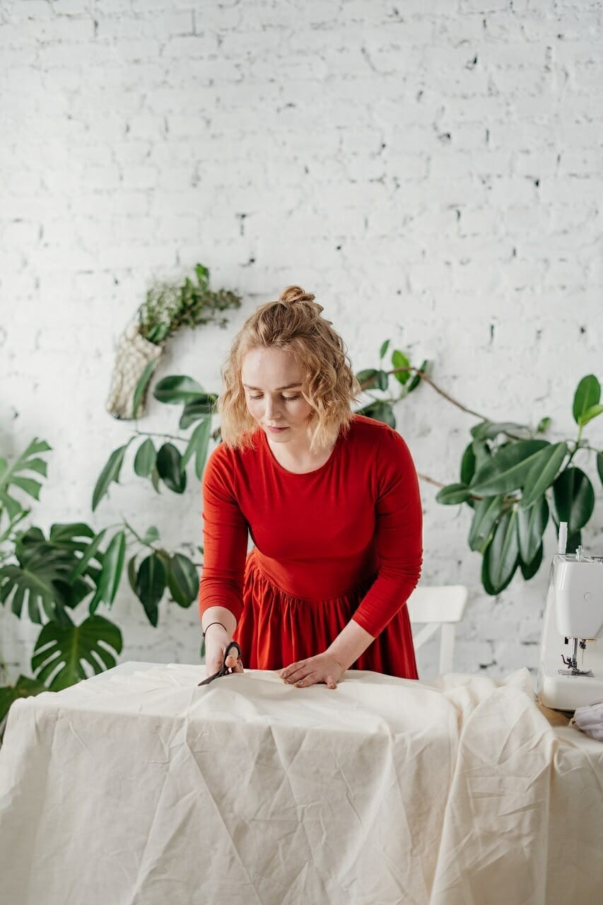 women in red dress cutting white cloth