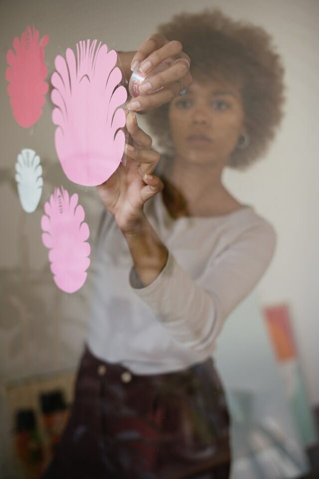 women sticking paper flowers on glass wall