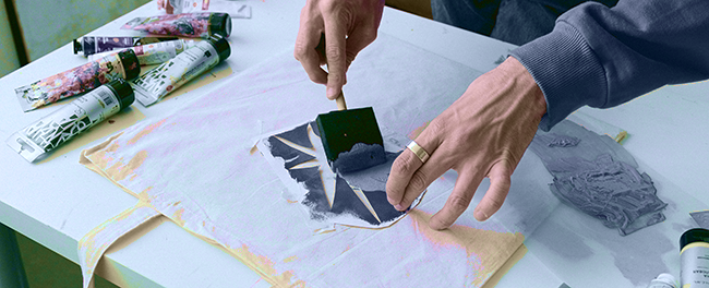 man painting a fabric bag with acrylic paint